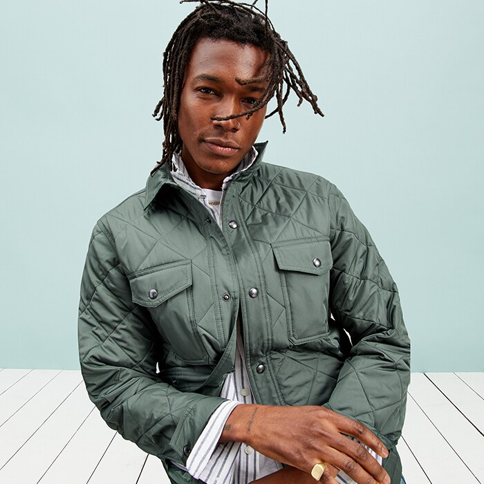 A male model wears a terrestrial green colored water-resistant quilted shacket
