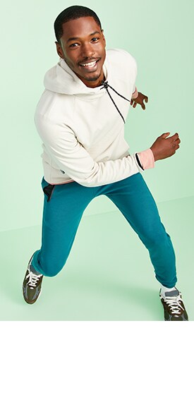A male model wears a light colored Dynamic Fleece pullover hoodie & teal colored Dynamic Fleece joggers