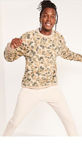 A male model wears a gender-neutral camo French terry sweatshirt and light colored activewear sweatpants