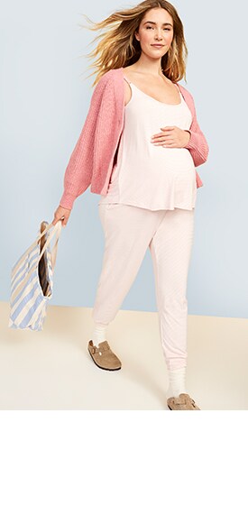 A maternity model wears a pink colored Maternity 4-Piece Sunday Sleep Essentials Kit under a dark pink zip-up hoodie.
