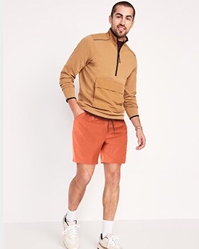 Un homme porte un chandail à glissière au quart  et un short de jogging StretchTech Go-Dry Shade rouge foncé.