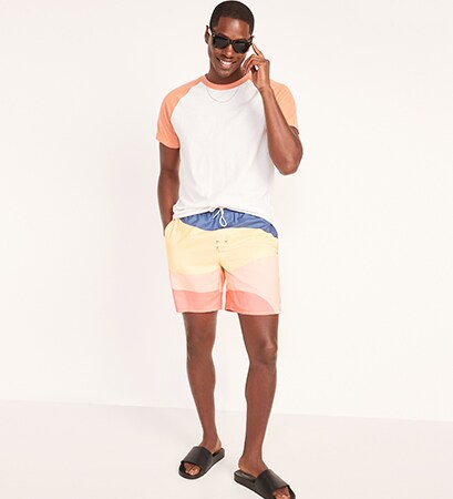 A male model wears a short sleeve white ringer t-shirt & 7 inch wave block swim trunks.