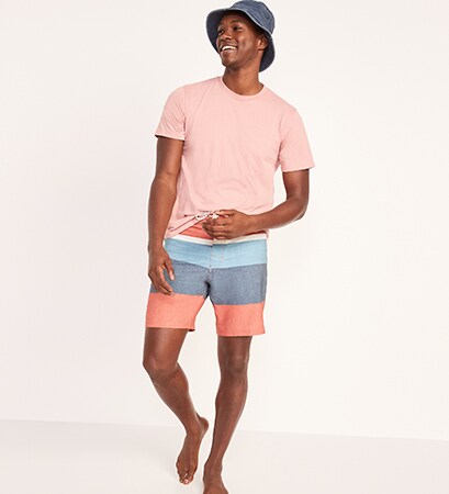 A male model wears a light pink short sleeve t-shirt & 8 inch color block board shorts.