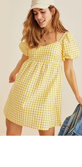 Une femme porte une robe All-Day jaune ajustée et évasée à fronces.