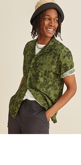 Un homme porte une chemise de camp à coupe décontractée en lin à motifs fleuris et manches courtes.