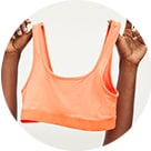 A female model holding up a bright orange t-shirt bra.