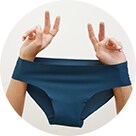 Une femme tient une culotte taille basse bleu foncé à la main.