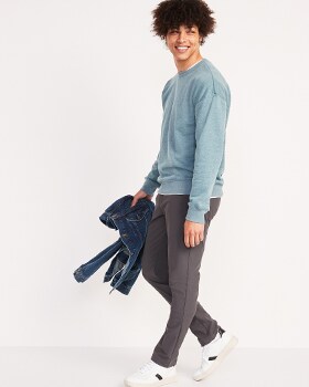A model wears a light blue crew neck sweatshirt and Hybrid style pants