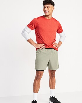 Un mannequin porte un t-shirt Core rouge et un short de sport.