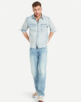 A male model wears Loose style jeans & a light washed chambrey button-up shirt.