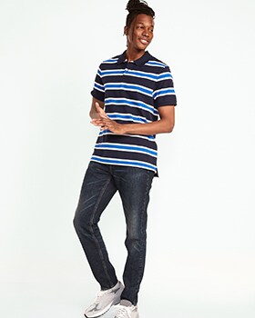 A male model wears Straight style jeans and a black, white & blue horizontal striped polo shirt.