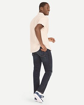 Un mannequin porte un jean étroit au fini foncé avec une chemise à manches courtes de couleur crème.