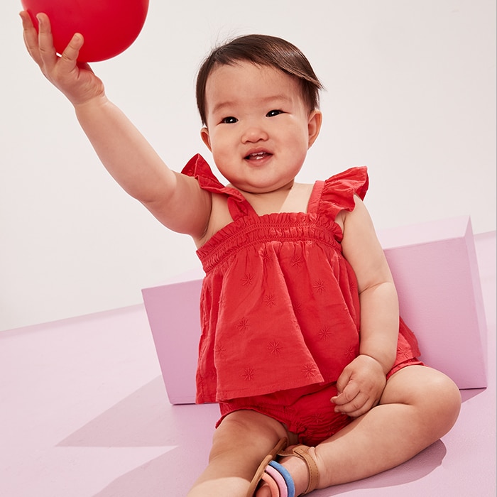 A baby girl model wearing red puffle-sleeve embroidered top & bloomer shorts set.