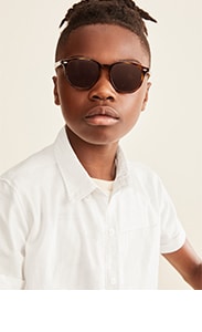 A young boy model wearing short sleeve white uniform shirt.