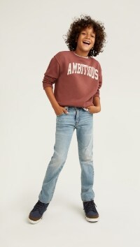 A male model wears Straight style jeans with a graphic print crewneck sweatshirt.