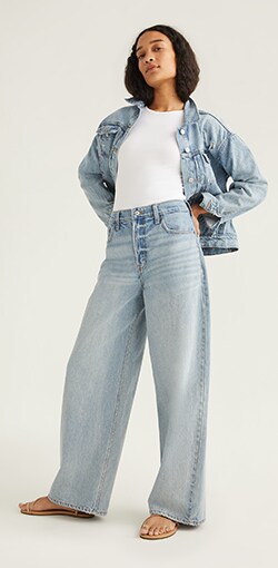 A female model in oversized light wash jeans.