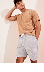 Un homme vêtu d’un t-shirt ultra-doux ras du cou brun pâle et d’un short de jogging décontracté en mélange de lin rayé.