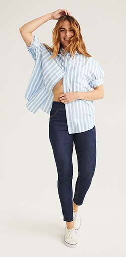 A model in a pinstripe button down with  curvy fit jeggings.