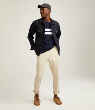 A male model wears light colored chino style pants and a dark denim jacket.