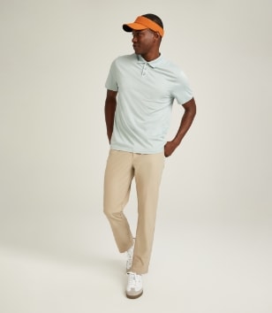 A male model wears a light colored polo shirt & light khaki activewear pants.