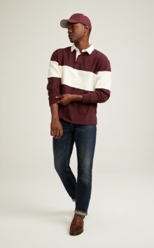 A male model wears Straight style jeans and a horizontal striped rugby shirt.