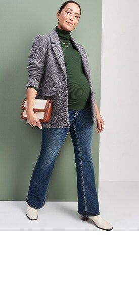 A maternity model wears a grey blaze, green turtleneck & maternity jeans.
