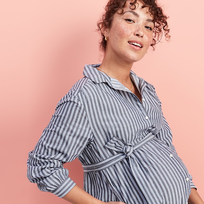 A maternity model wearing a vertical striped maternity outfit