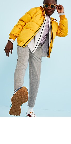 A young model wearing Old Navy activewear for boys yellow jacket and grey sweatpants.