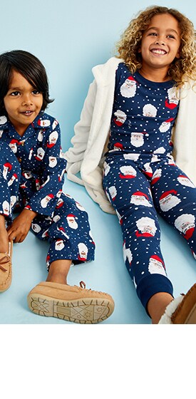 De jeunes mannequins assis portent un pyjama de père Noël et des pantoufles Old Navy.
