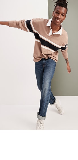 A male model wears a horizontal striped rugby shirt & dark wash jeans.