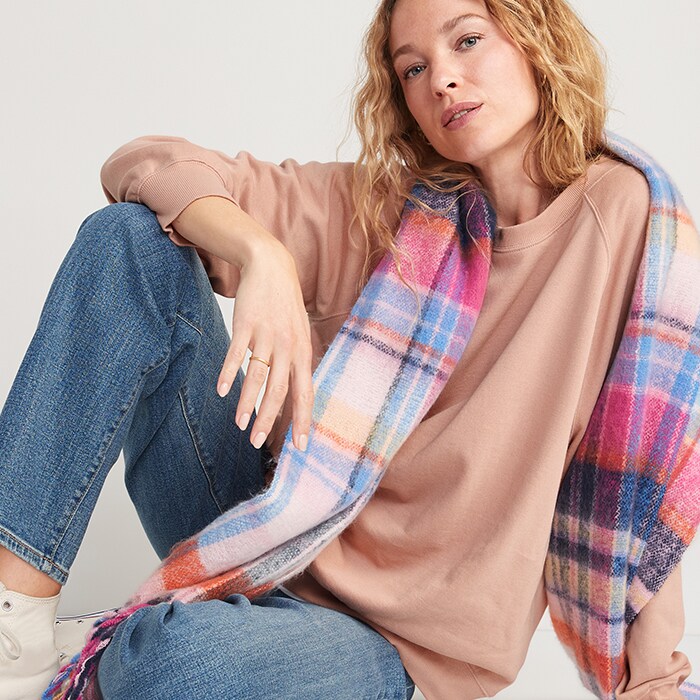 A female model wears Old Navy Sale items including tan sweatshirt, plaid scarf and jeans.