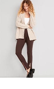 A female model wears brown split hem pants with a white top and cream colored cardigan.