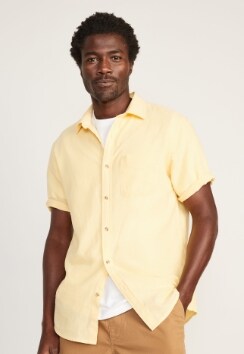 A male models wears a light yellow short-sleeve linen button-up shirt.