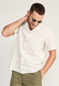 A male model wears a light colored vertical stripe short-sleeve Resort style button-up shirt.