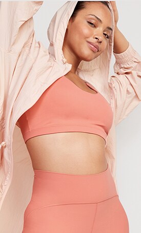 A female model wearing a light pink Medium-Support PowerSoft Racerback Sports Bra & matching activewear bottoms