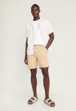 A male model wears a light colored Relaxed Ultimate Tech Chino Shorts for Men -- 9-inch inseam