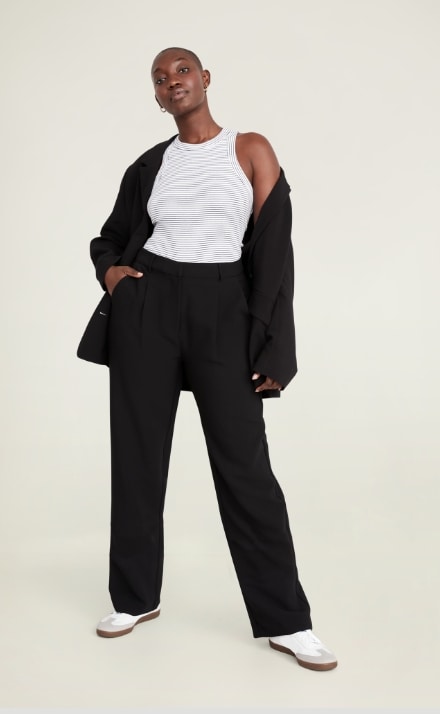A female model wearing black colored pants & matching top