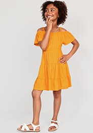 Young model wearing orange cold-shoulder tiered swing dress for girls.