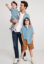 Male model with two young boys wearing matching blue short-sleeve printed camp shirt.